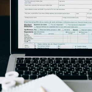  Close-up of a laptop displaying the 2020 U.S. Individual Income Tax Return (Form 1040) with fields for filing status and personal information visible.