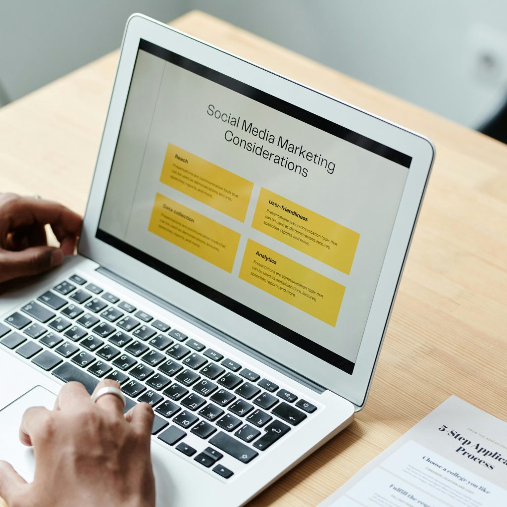 A person uses a laptop displaying a presentation slide titled "Social Media Marketing Considerations" with four yellow-highlighted points.