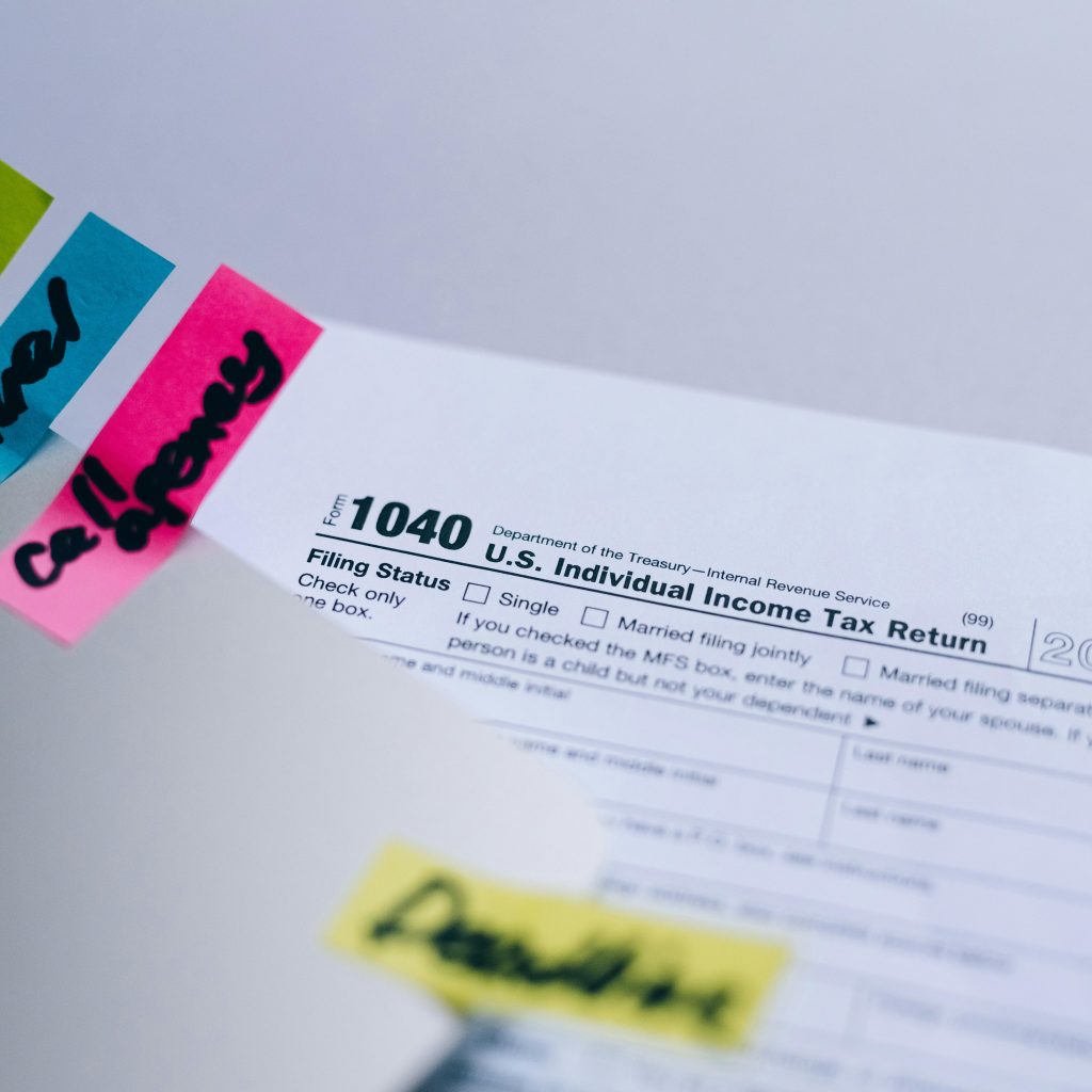 A close-up of a US 1040 Individual Income Tax Return form for 2020, with colorful sticky notes reading Tax, Annual, and California.